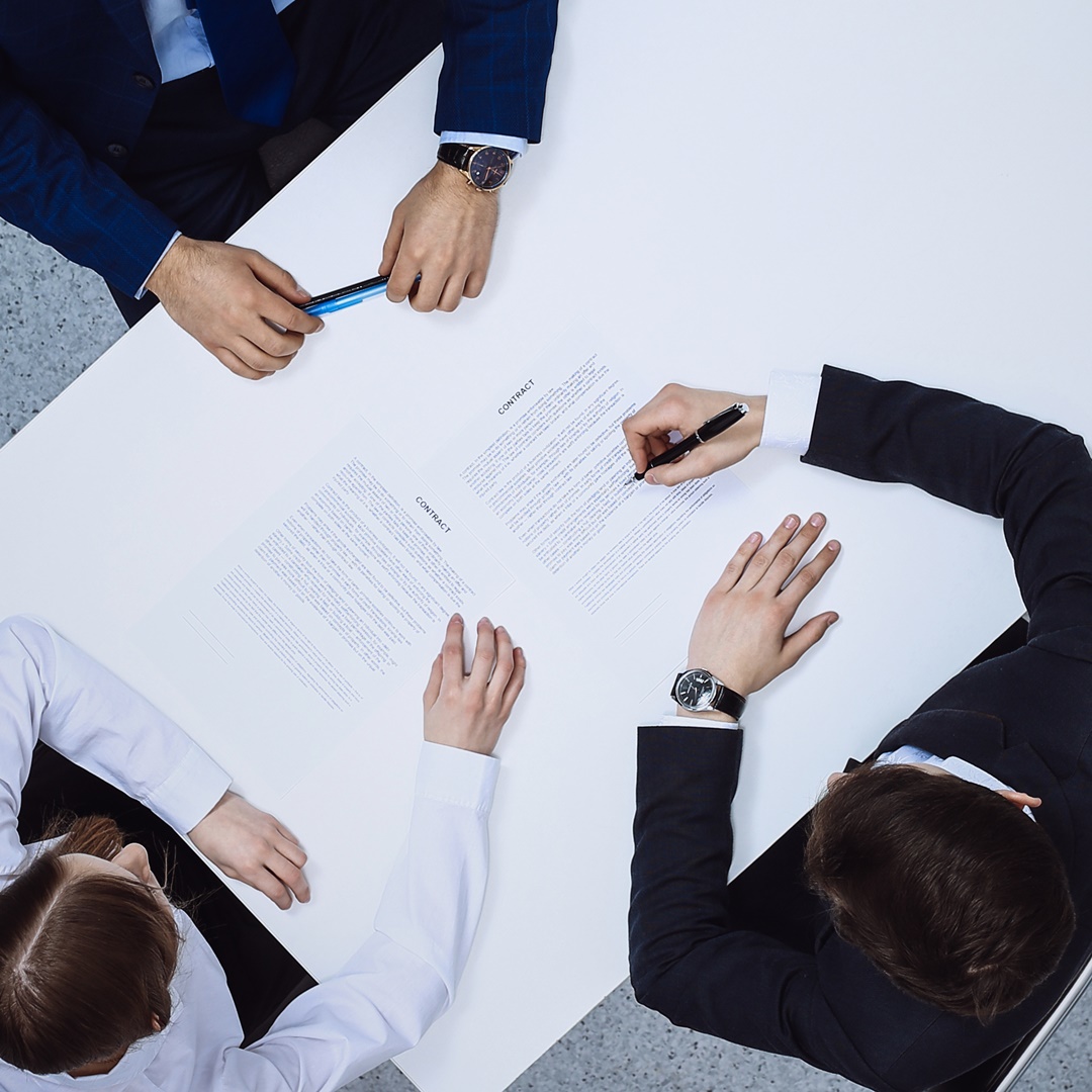 Group of business people and lawyer discussing contract papers sitting at the table, view from above. Businessman is signing document after agreement done